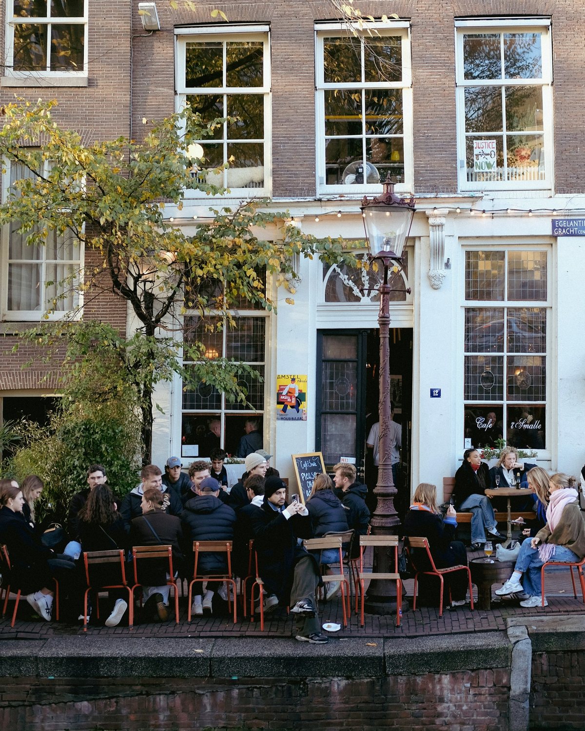 Terras aan een Amsterdamse gracht in de herfst, met vrienden aan tafel